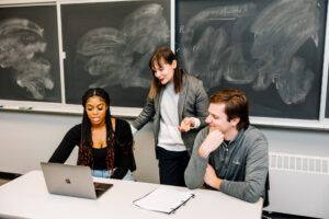 Students work with a professor in front of a blackboard