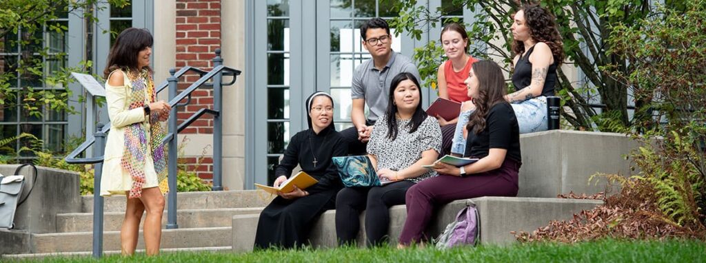 A professor, a nun, and students chat outdoors
